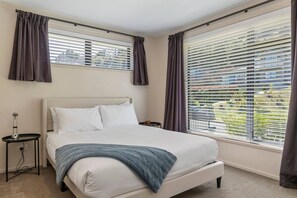 Un dormitorio con cama, mesita de noche y ventana con persianas.
