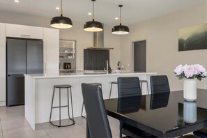 A modern kitchen with a central island, black bar stools, and pendant lighting.