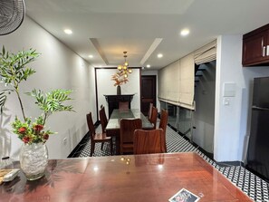 Una cocina moderna con comedor, que presenta una mesa de madera, sillas, un jarrón con flores y una lámpara colgante.