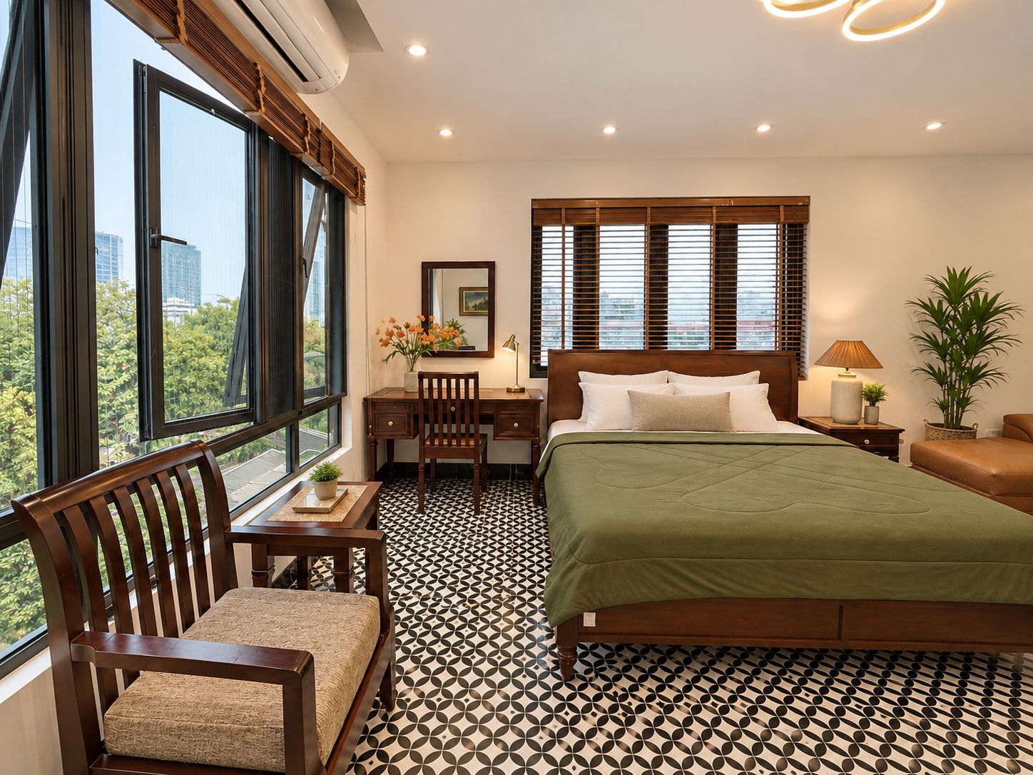 Ein Hotelzimmer mit Bett, Schreibtisch, Stuhl, Nachttisch, Lampe und einem Fenster mit Jalousien.