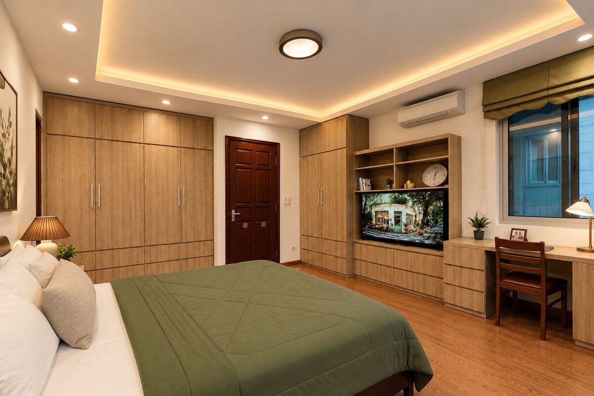 A bedroom with a bed, a desk, and a television.