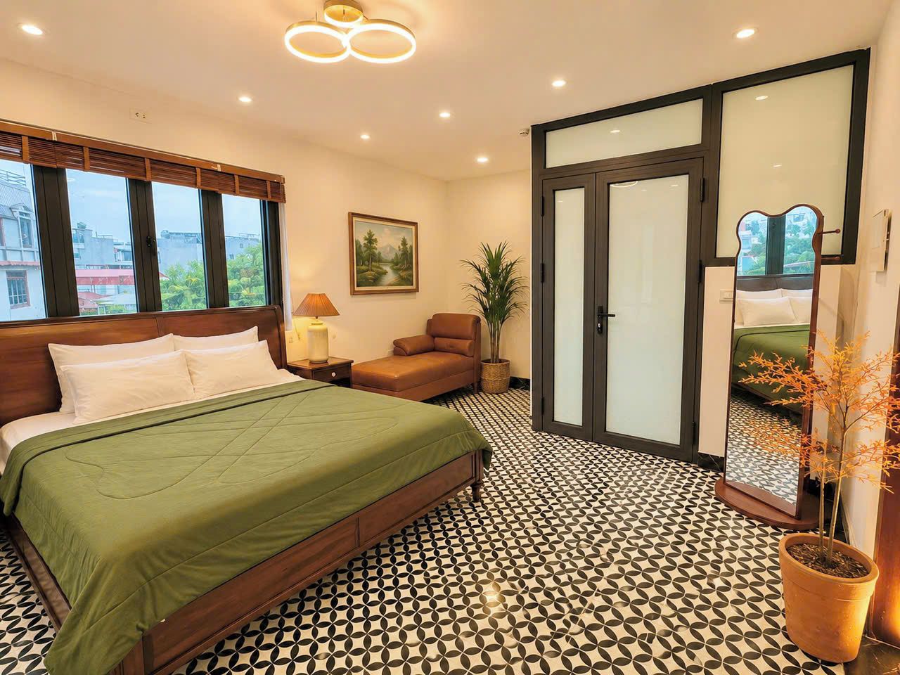 Quarto com cama, cadeira, luminária, pintura e planta em vaso.