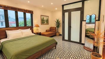 Quarto com cama, cadeira, luminária, pintura e planta em vaso.