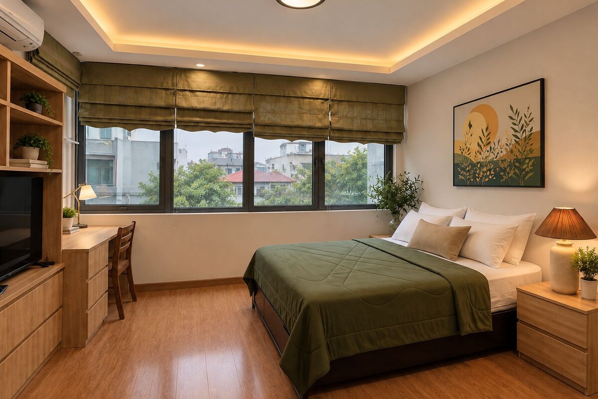 A bedroom with a bed, bedside table, lamp, and a desk with a chair.