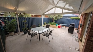 A covered patio area with a table and chairs, a barbecue grill, and potted plants. - 2 bed 1 bath house in the heart of Bayswater! (Bayswater)