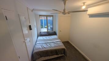 A bedroom with a bed, a ceiling fan, a window, and a door.