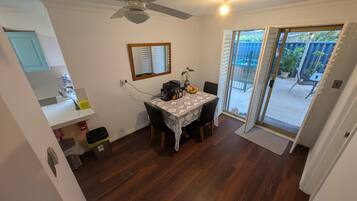 A dining area with a table, chairs, a ceiling fan, and a view of the backyard through a sliding glass door.