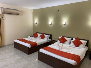 Habitación de hotel con dos camas, cada una con ropa de cama blanca y detalles en rojo, aire acondicionado de pared y lámparas de noche.