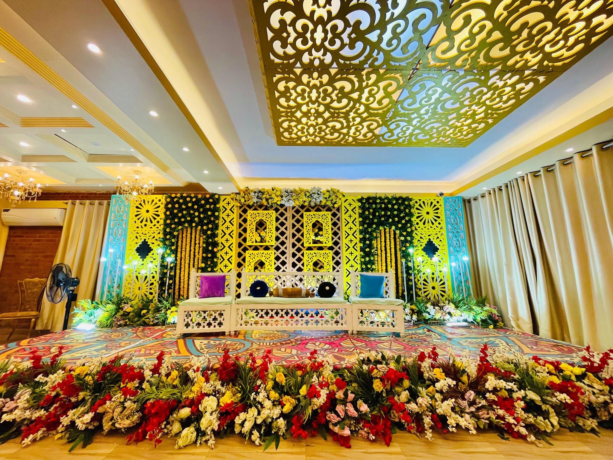 Um palco com arranjo floral, área de estar e teto decorativo.