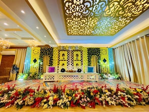 A stage with a floral arrangement, a seating area, and a decorative ceiling.