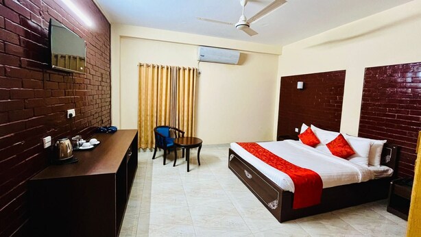 Habitación de hotel con cama, escritorio, silla, ventilador de techo y ventana con cortinas.
