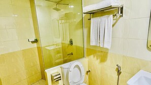 Un baño con ducha envuelta en vidrio, inodoro, lavabo y perchero para toallas.
