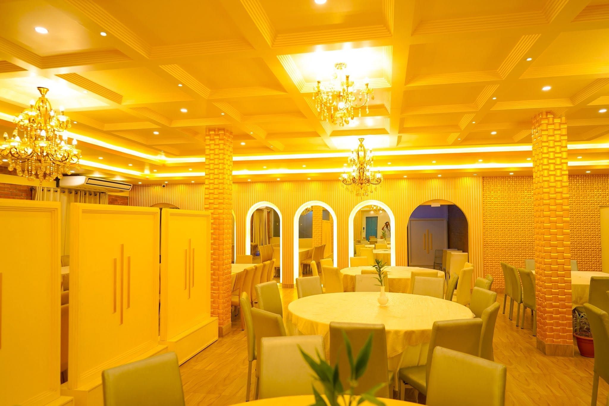 Uma sala de jantar com mesas redondas, cadeiras e um lustre.