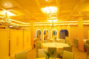A dining area with round tables, chairs, and a chandelier.