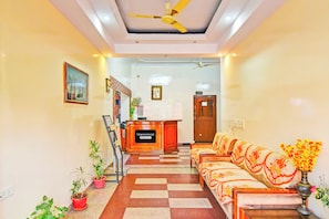 A reception area with a check-in counter, a sofa, and a ceiling fan. - Townhouse Hathroi Market (Jaipur)
