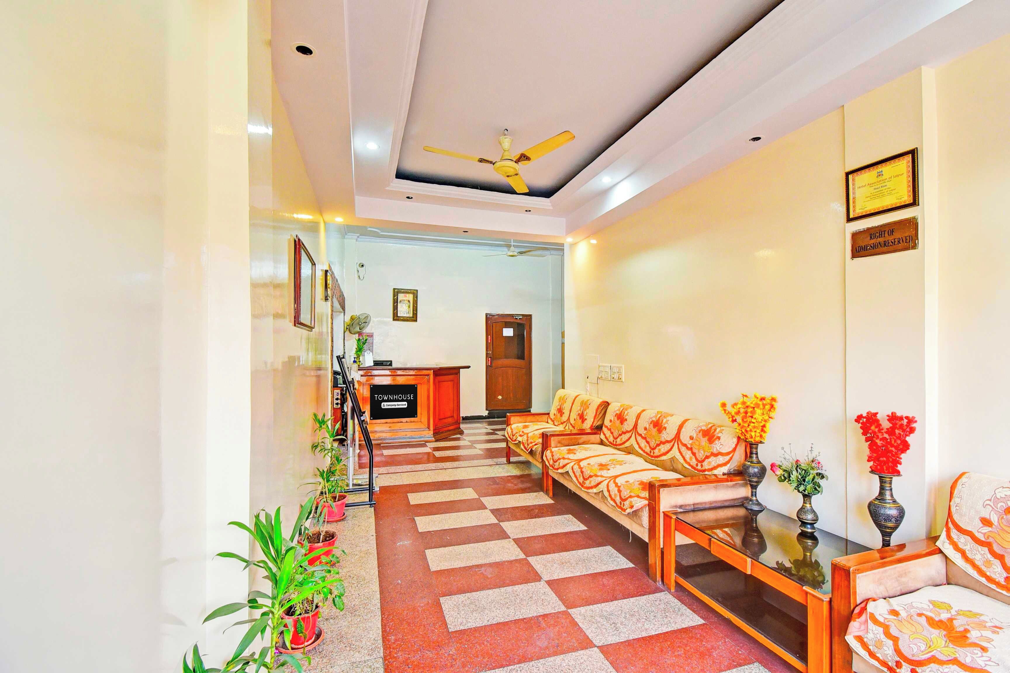 A hotel lobby with a reception desk, check-in counters, a seating area with sofas, and a checkered floor.