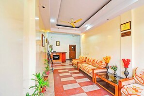 A hotel lobby with a reception desk, check-in counters, a seating area with sofas, and a checkered floor.
