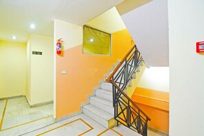 A staircase with a handrail, a fire extinguisher mounted on the wall, and a sign indicating room numbers 106 to 109.