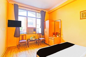 A room with a bed, a desk, two chairs, a television, and a window with curtains. - Townhouse Hathroi Market (Jaipur)