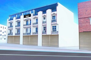 A multi-story building with balconies, a sign indicating it's a company serviced townhouse, and closed garage doors.