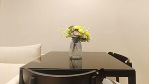Une table à manger avec un vase de fleurs, une chaise et un coussin.