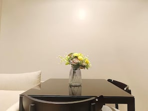 A dining table with a vase of flowers, a chair, and a pillow. - Tierra Residences in Bangkok (Krung Thep Maha Nakhon)