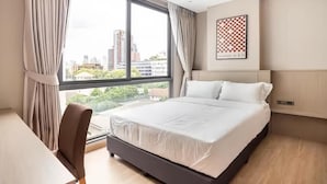 Une chambre d’hôtel avec une grande fenêtre, un lit, un bureau et une chaise.