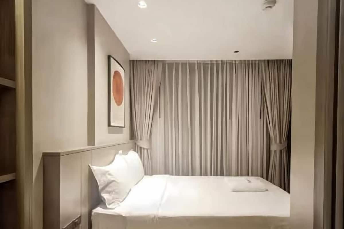 A bedroom with a bed, a headboard, a bedside table, and a wall-mounted picture.