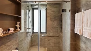 Une salle de bain moderne avec une douche à parois de verre, des carreaux de marbre et un porte-serviettes.