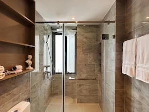 A modern bathroom with a glass-enclosed shower, marble tiles, and a towel rack. - Tierra Residences in Bangkok (Krung Thep Maha Nakhon)