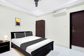 A modern bedroom with a bed, bedside table, lamp, wardrobe, and an air conditioning unit. - Townhouse Oak Taj Nagri Phase 2 (Agra)