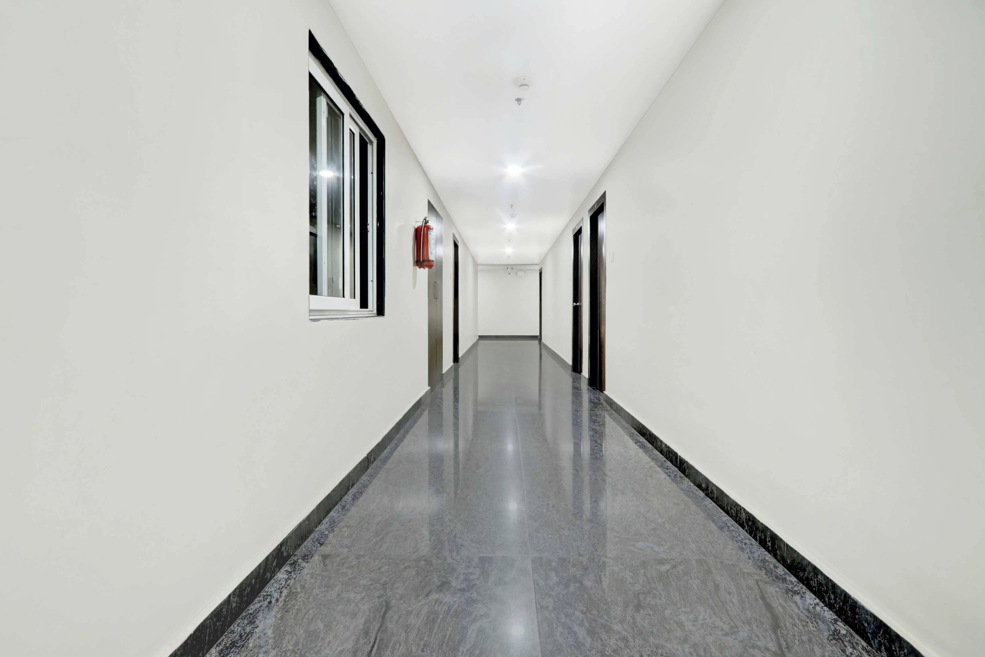 Un pasillo largo y estrecho con paredes blancas y piso pulido.
