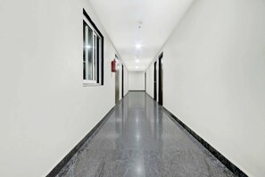 Un pasillo largo y estrecho con paredes blancas y piso pulido.