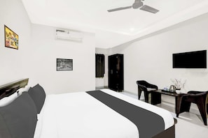 A modern hotel room with a bed, a desk, a chair, a TV, and a ceiling fan. - Townhouse Oak Taj Nagri Phase 2 (Agra)