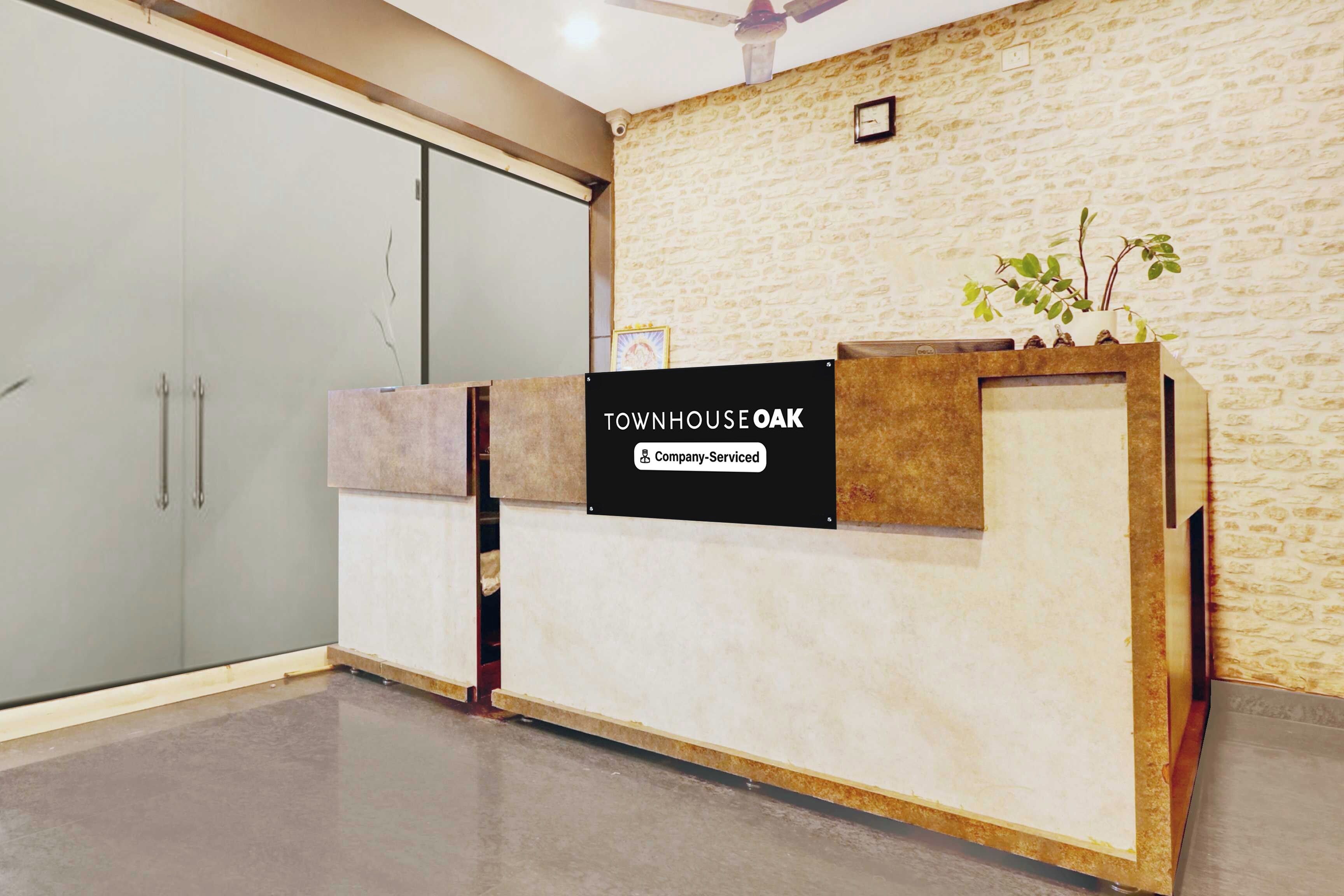 Een receptiebalie met een bord waarop 'TOWNHOUSE OAK Company-Serviced' staat.