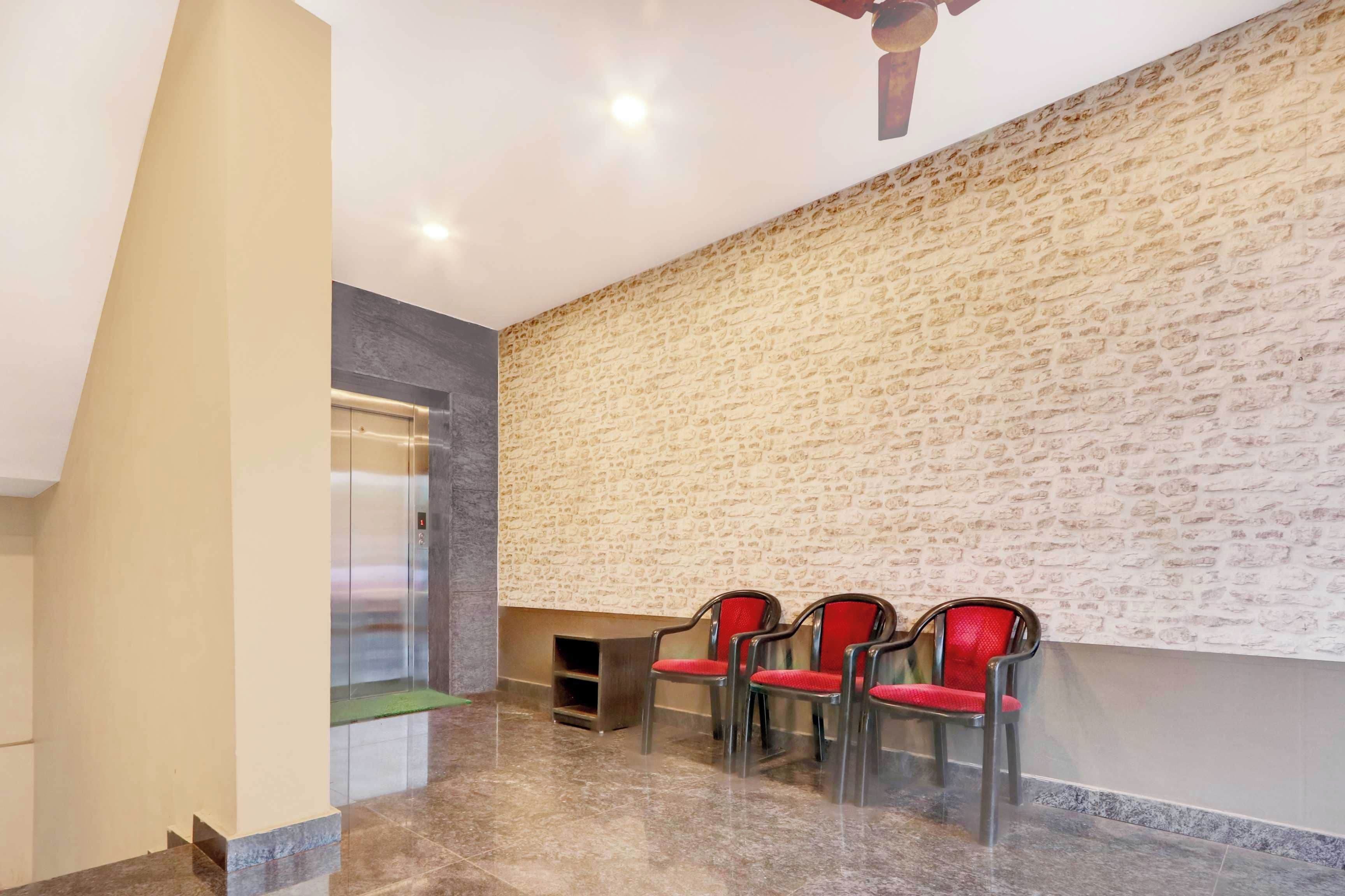 Vestíbulo con pared de piedra, mostrador de recepción y zona de estar con sillones.