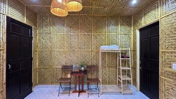 Een kamer met een wand in bamboestijl, een houten tafel met stoelen, een hanglamp en een schoenenrek.