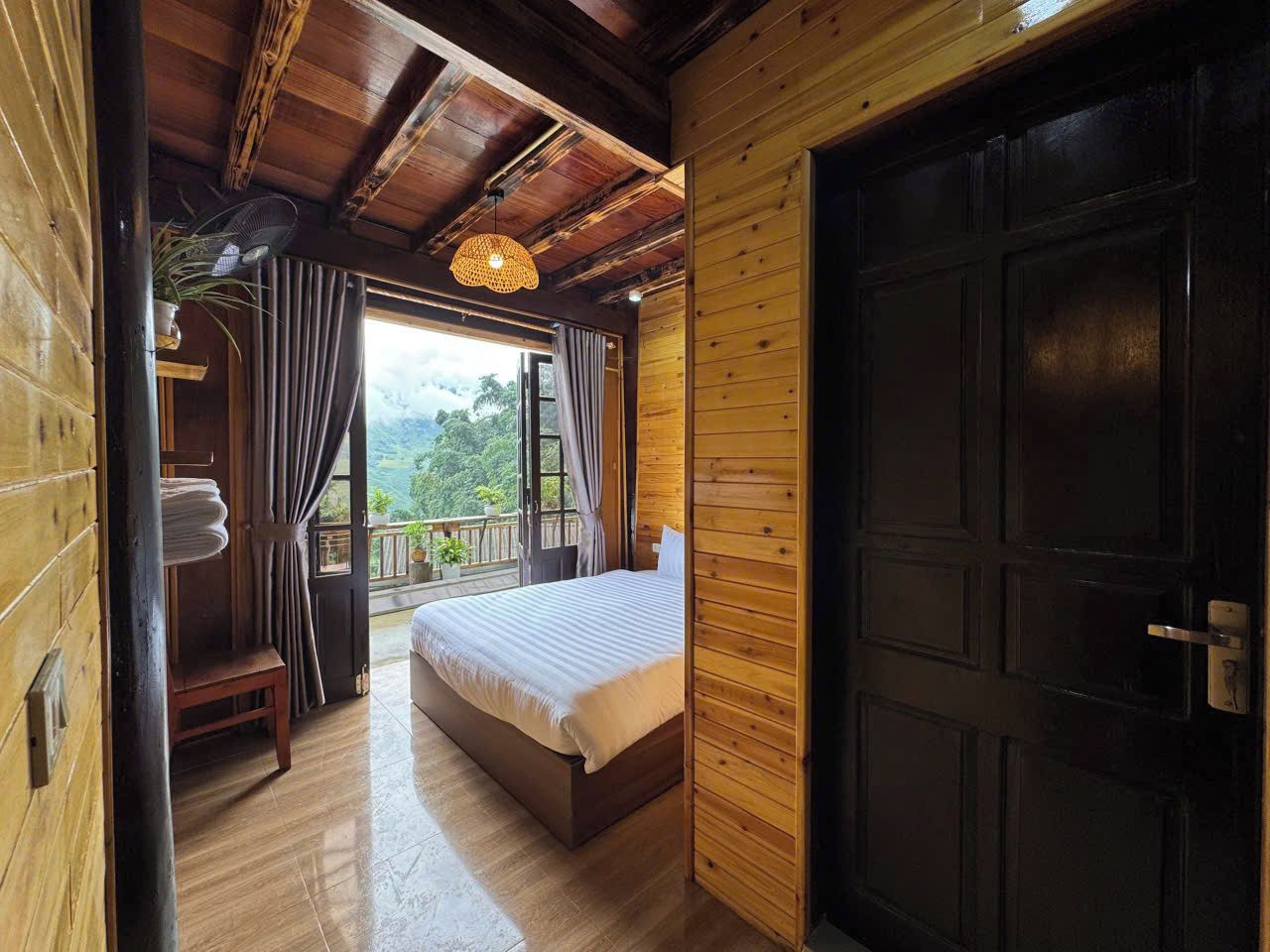 Una habitación de madera con una cama, una puerta y vistas al exterior.