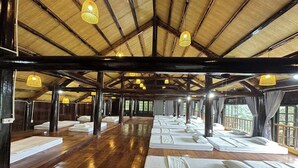 A large room with wooden floors and a high ceiling, featuring multiple beds arranged in rows. - Suoi Sapa Homestay And Trekking (Ta Van)