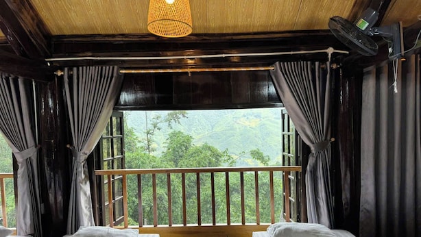 A room with two beds, a wooden ceiling, a view of greenery outside, and a hanging light fixture. - Suoi Sapa Homestay And Trekking (Ta Van)