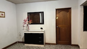 A room with a white dresser, a mirror above it, a wooden door, and a small framed picture on the wall.