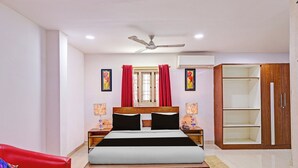 A hotel room with a bed, a red chair, a wardrobe, and a ceiling fan. - Townhouse Seethammadhara Junction (Visakhapatnam)