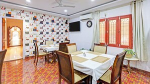 A dining area with a ceiling fan, a wall-mounted TV, and a patterned wall. - Townhouse Seethammadhara Junction (Visakhapatnam)