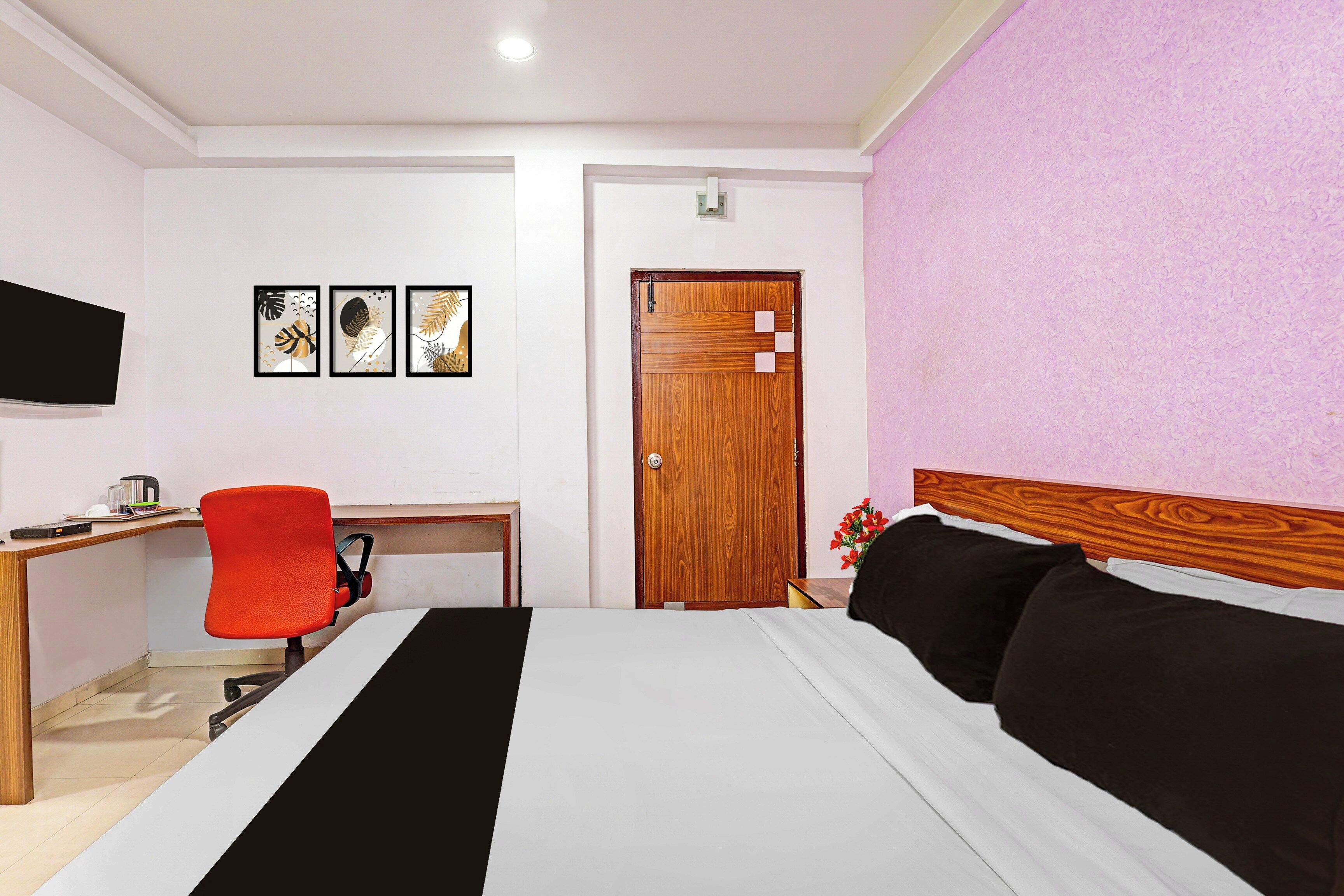 A hotel room with a bed, a desk, a chair, a television, and a door.