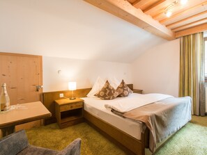 A cozy bedroom with a wooden bed, a nightstand, a lamp, and a bottle of champagne. - Haus am Brunnen, (Samnaun-Compatsch) by Interhome (Samnaun)