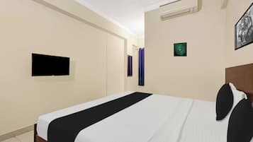A hotel room with a bed, a flat-screen TV, an air conditioner, and a framed picture on the wall.