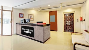 Una mesa de recepción con el rótulo 'TOWNHOUSE Company-Serviced', una computadora, un retrato enmarcado y un icono religioso en la pared.