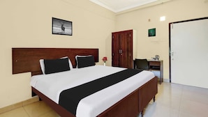 Habitación de hotel con una cama grande, un escritorio con silla, un armario y una puerta.
