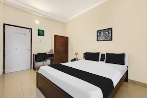Habitación de hotel con cama, escritorio, silla, armario y un cuadro en la pared.