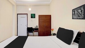 Habitación de hotel con cama, escritorio, silla, armario y una obra de arte en la pared.